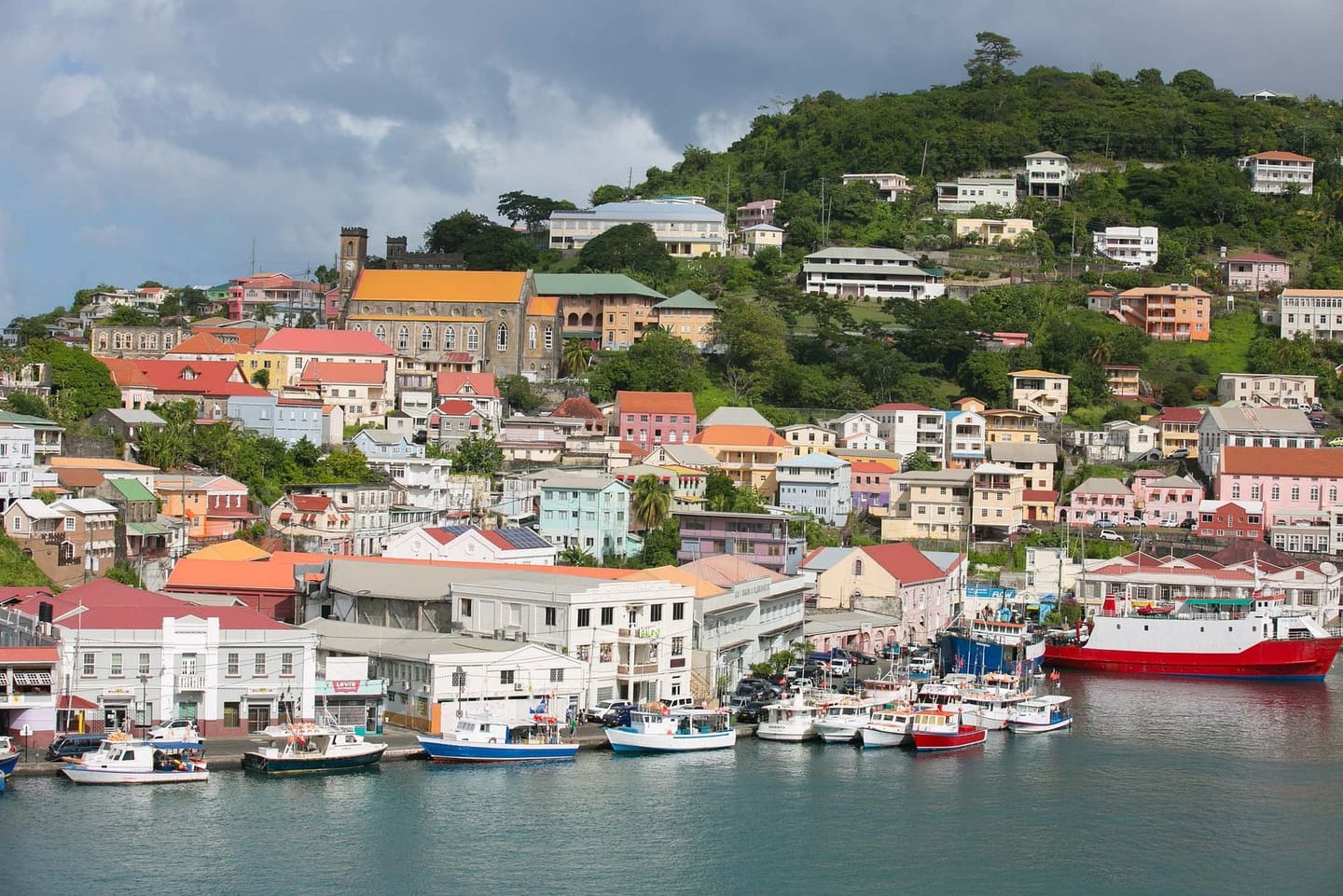 Colourful hillside town and harbour in Grenada, with fishing boats moored along the waterfront