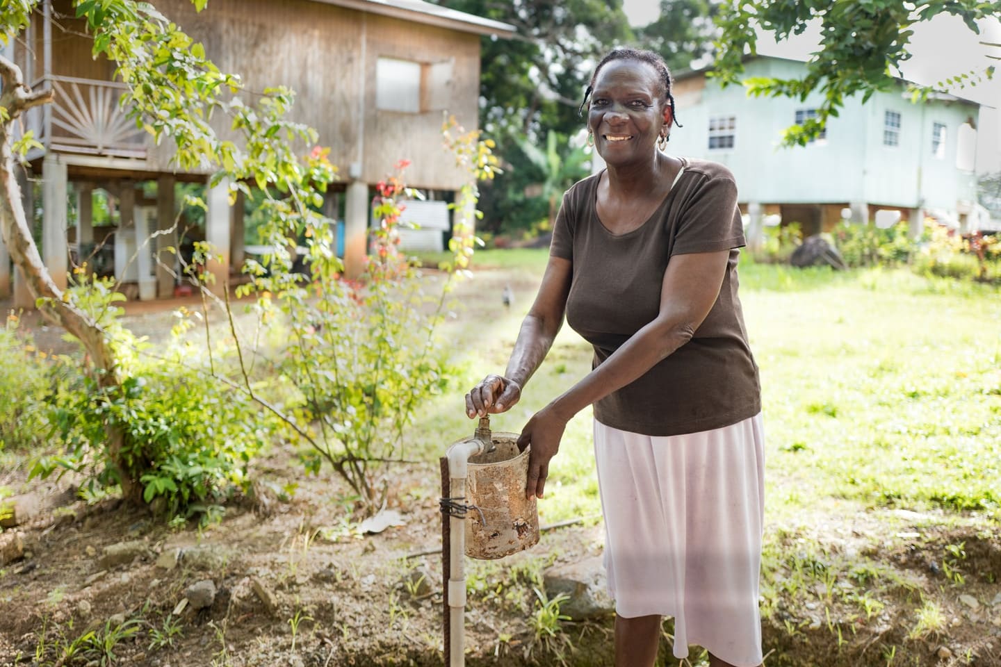 A woman turning on a standpipe tap outside her home in Saint Lucia