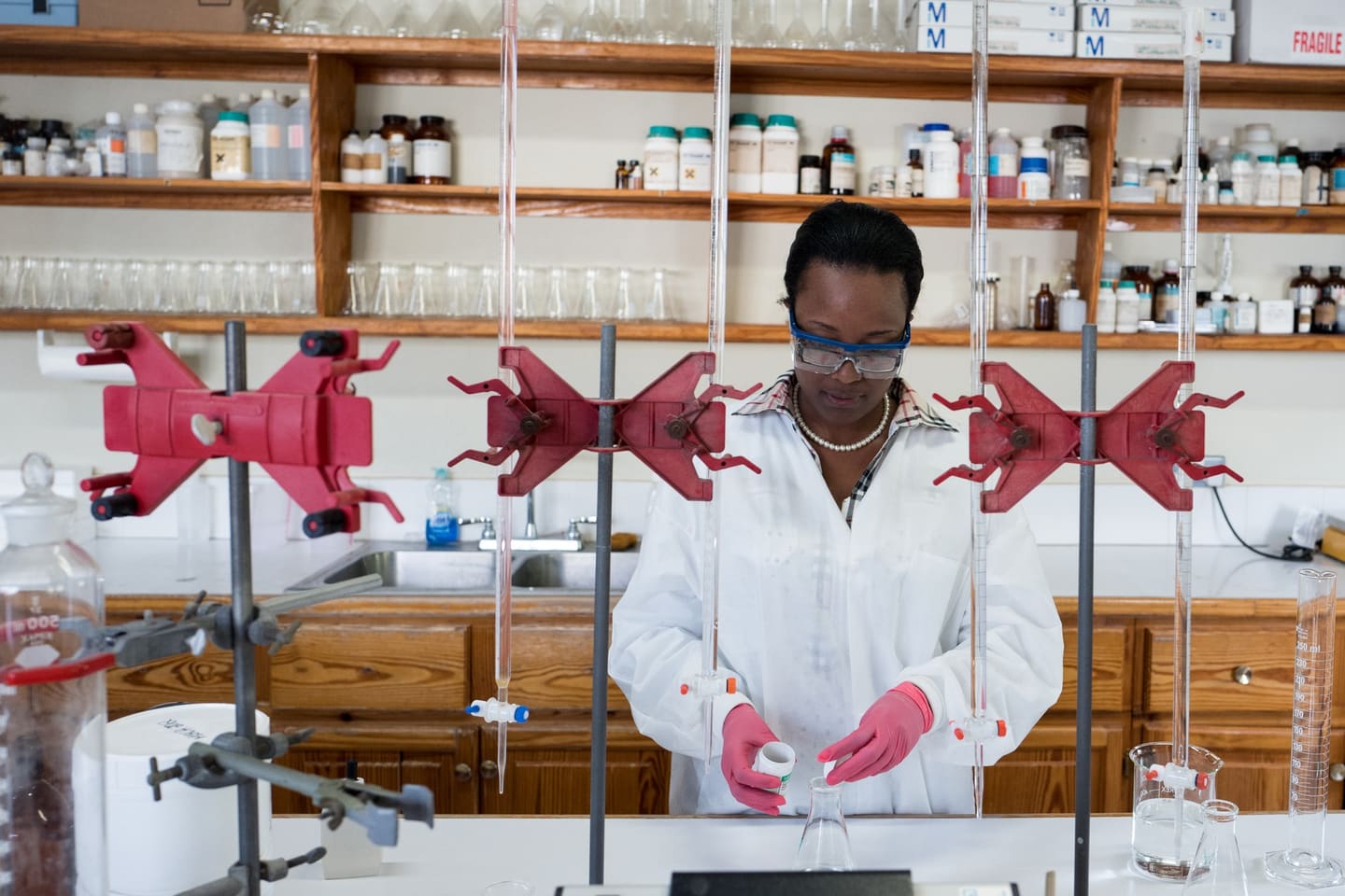 A scientist in a laboratory in the Caribbean, measuring a sample into a flask