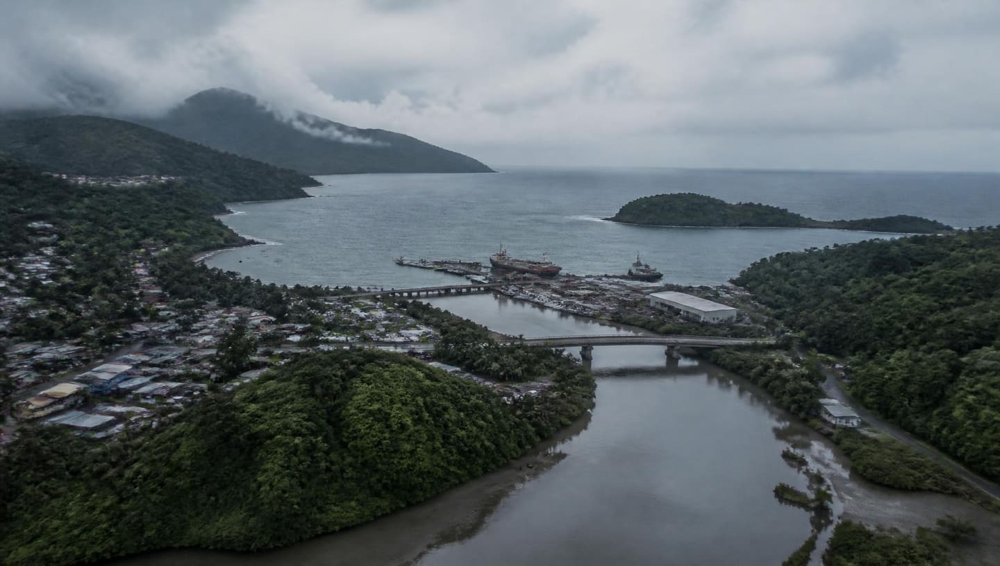 Aerial view of a Caribbean island port, river outlet and road bridge