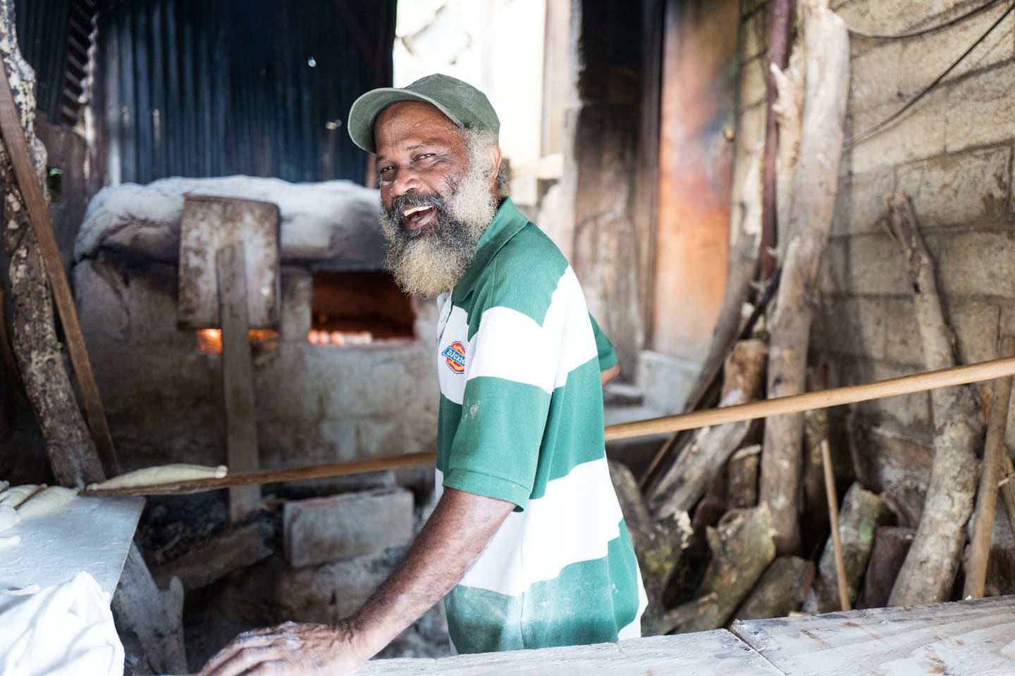 A baker beside a traditional wood-fired bread oven in Saint Lucia